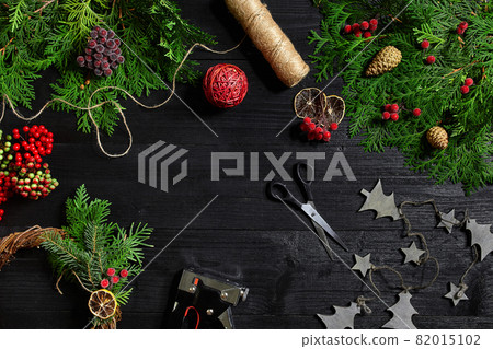 Make a Christmas wreath with your own hands. Spruce branch, Christmas wreath and gifts on a black wooden background Make a Christmas wreath with your own hands. Spruce branch, Christmas wreath and gifts on a black wooden background 82015102