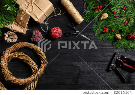 Make a Christmas wreath with your own hands. Spruce branch, Christmas wreath and gifts on a black wooden background 82015164