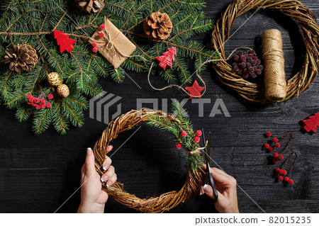 Manufacturer of Christmas decor with their own hands. Christmas wreath for the holiday. The new year celebration. Top view Manufacturer of Christmas decor with their own hands. Christmas wreath for the holiday. The new year celebration. Top view 82015235