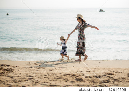 Mother and daughter having fun on the beach 82016506