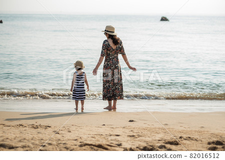 Mother and daughter having fun on the beach 82016512