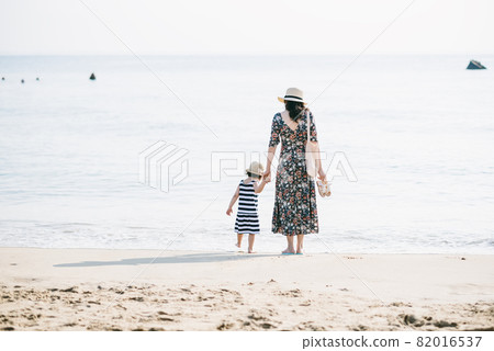 Mother and daughter having fun on the beach 82016537