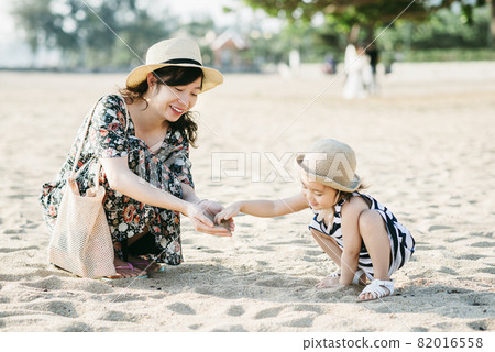 Mother and daughter having fun on the beach 82016558