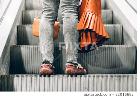Legs standing on the escalator of a shopping mall Legs standing on the escalator of a shopping mall 82016692