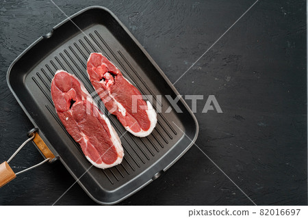 Raw steak on frying grill pan. Dark background. Raw steak on frying grill pan. Dark background. 82016697