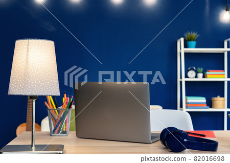 Working table with laptop against blue wall in modern flat Working table with laptop against blue wall in modern flat 82016698
