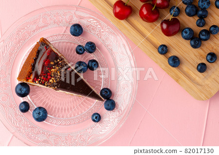 Piece of cheesecake with chocolate top and berries 82017130
