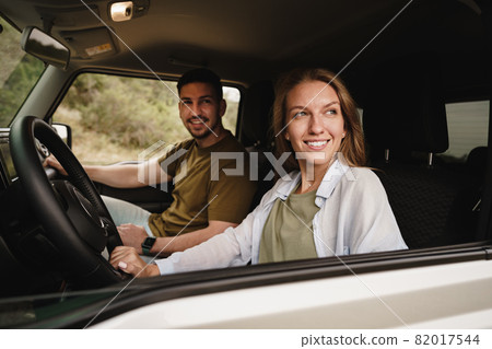 Beautiful young couple sitting on front passenger seats and driving a car Beautiful young couple sitting on front passenger seats and driving a car 82017544