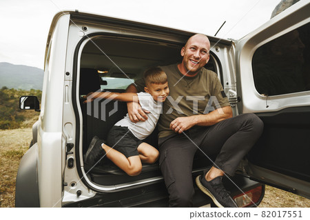 Happy father and son sitting in car trunk Happy father and son sitting in car trunk 82017551