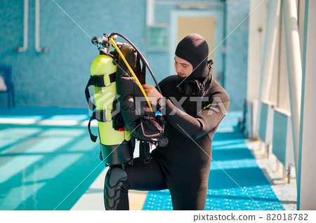 Male diver puts on oxygen tank, diving school Male diver puts on oxygen tank, diving school 82018782