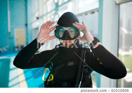 Female diver in scuba suit sitting at the poolside 82018806