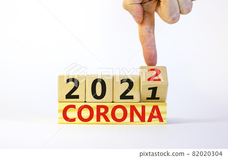 Symbol of covid-19 pandemic in 2022. Doctor turns a wooden cube and changes words 'corona 2021' to 'corona 2022'. Beautiful white background, copy space. Medical, covid-19 pandemic in 2022 concept. 82020304