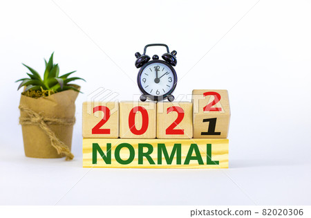 Symbol of covid-19 normal in 2022. Alarm clock. Turned a wooden cube, changed words 'normal 2021' to 'normal 2022'. Beautiful white background, copy space. Medical, covid-19 normal in 2022 concept. Symbol of covid-19 normal in 2022. Alarm clock. Turned a wooden cube, changed words 'normal 2021' to 'normal 2022'. Beautiful white background, copy space. Medical, covid-19 normal in 2022 concept. 82020306