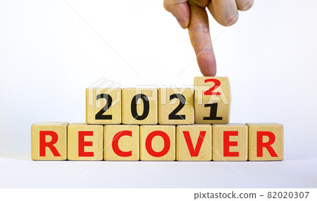 Symbol of planning 2022 recover new year. Businessman turns a wooden cube and changes words 'recover 2021' to 'recover 2022'. Beautiful white background, copy space. Business, 2022 recover concept. 82020307