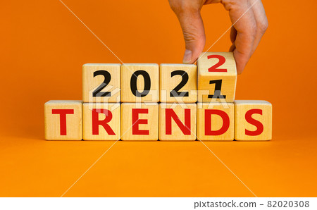 Trends 2022 new year symbol. Businessman turns wooden cubes, changes words 'Trends 2021' to 'Trends 2022'. Beautiful orange background, copy space. Business and trends 2022 new year concept. 82020308