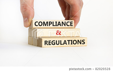Compliance and regulations symbol. Concept words 'Compliance and regulations' on wooden blocks, beautiful white background. Businessman hand. Business, compliance and regulations concept. Copy space. 82020328