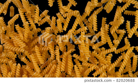 Freeze motion of flying uncooked italian pasta fusilli on black background. Freeze motion of flying uncooked italian pasta fusilli on black background. 82020688