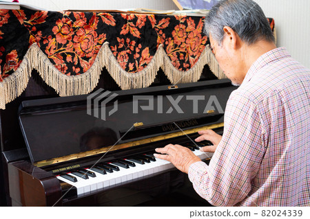 Senior man playing the piano as a hobby 82024339