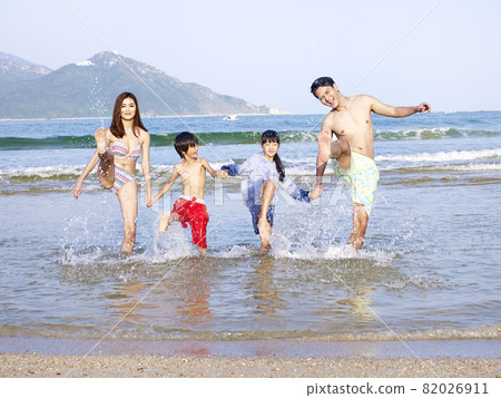 asian family with two children playing in the water on beach 82026911