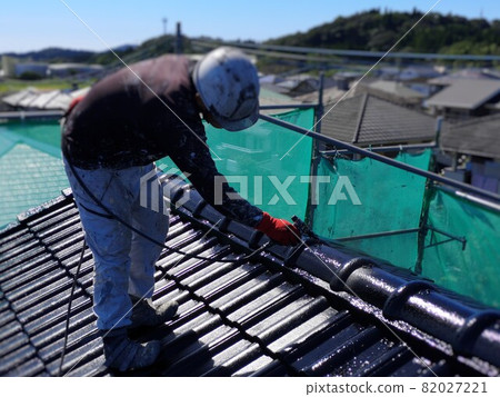 A male painter who paints roof tiles with an airless painter 82027221