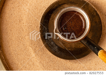 Copper turk with coffee brewing in sand 82027553