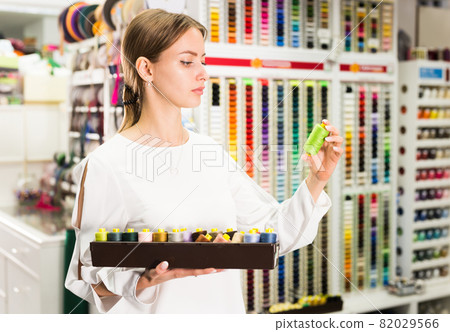 Girl choosing threads in store Girl choosing threads in store 82029566