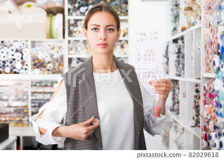 Woman choosing buttons in needlecraft store Woman choosing buttons in needlecraft store 82029618