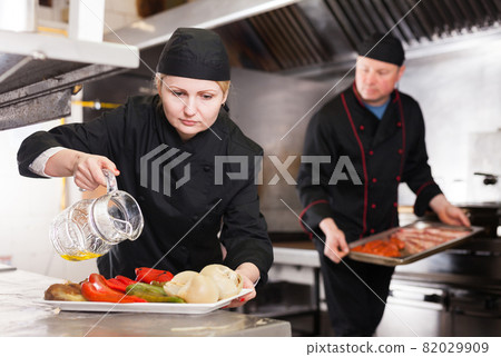 Female chef seasoning dish with oil Female chef seasoning dish with oil 82029909