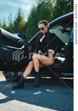 Racer woman by the opened door of a powerful car 82033481