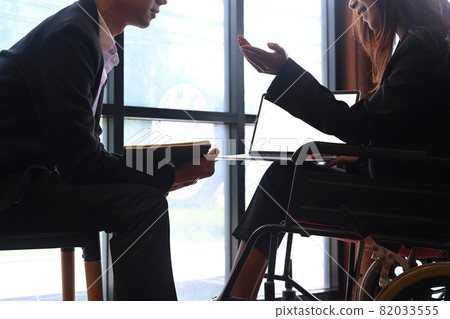 Cropped shot disabled female discussing work with her colleague in a modern office. 82033555