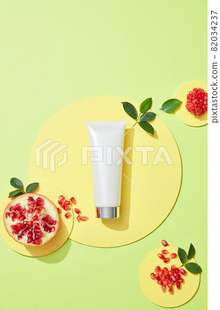 Empty podium for cosmetics with ingredients of red pomegranate extract and pomegranate seeds, flakes and leaves on light green background Empty podium for cosmetics with ingredients of red pomegranate extract and pomegranate seeds, flakes and leaves on light green background 82034237
