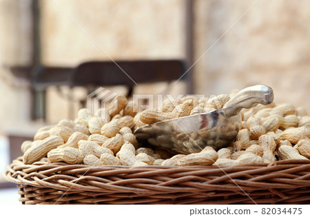 Wicker basket of raw organic peanuts in shell with metal scoop at outdoor market, copy space 82034475
