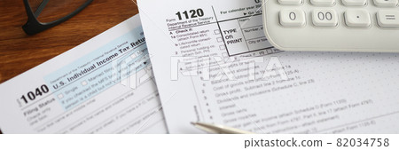 Tax forms with calculator and pen lying on table closeup Tax forms with calculator and pen lying on table closeup 82034758