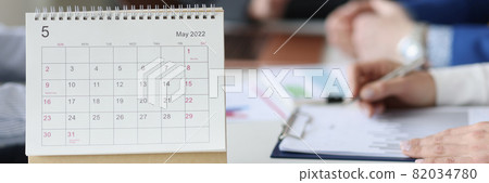 Loose leaf paper calendar standing on table against background of business people closeup 82034780
