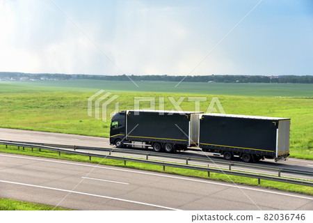 Rigid Truck and Drawbar Trailer driving along highway on the green agriculture field background. Rigid Truck and Drawbar Trailer driving along highway on the green agriculture field background. 82036746