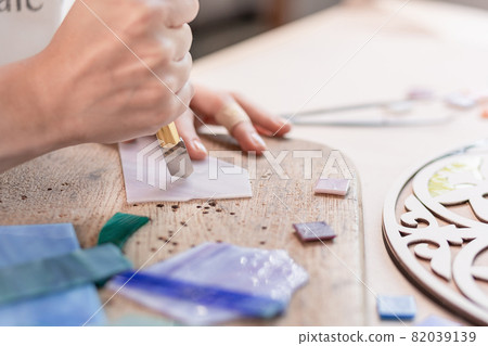 Artist cutting sheets of stained glass into small mosaic squares. Close-up 82039139