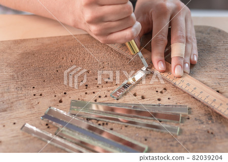 Artist cutting sheets of stained glass into small mosaic squares. Close-up 82039204