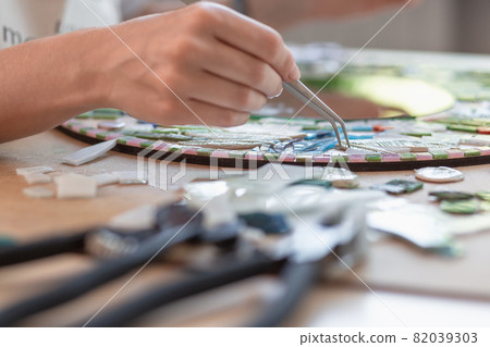Hands of master working on new modern colorful mosaic. Close-up 82039303