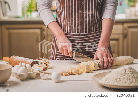 Close-up view of two woman's hands cut knife dough 82040051