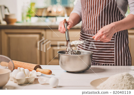 Young woman holding bowl with dough and whisk, closeup 82040119