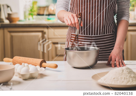 Young woman holding bowl with dough and whisk, closeup Young woman holding bowl with dough and whisk, closeup 82040138