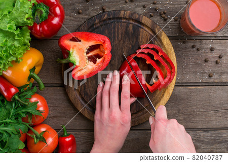 Female hands cutting pepper at table, top view Female hands cutting pepper at table, top view 82040787