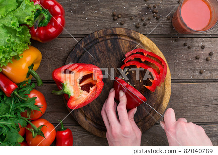 Female hands cutting pepper at table, top view Female hands cutting pepper at table, top view 82040789
