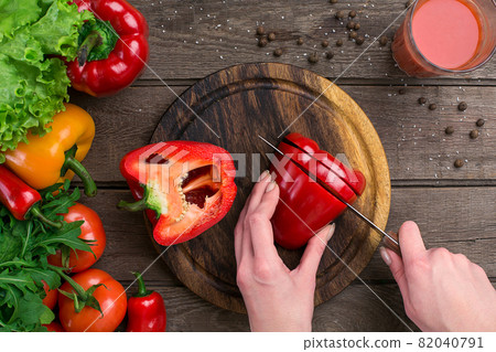 Female hands cutting pepper at table, top view Female hands cutting pepper at table, top view 82040791