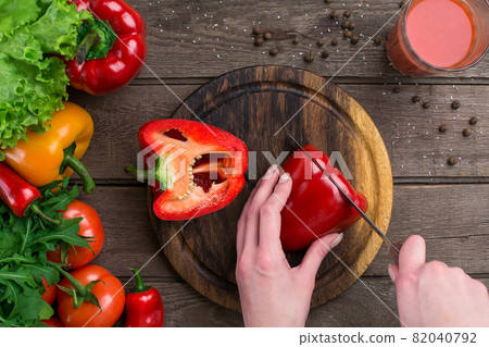Female hands cutting pepper at table, top view Female hands cutting pepper at table, top view 82040792