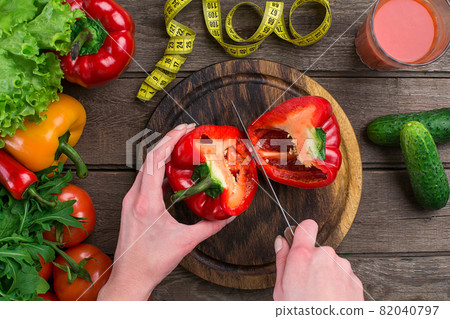 Female hands cutting pepper at table, top view Female hands cutting pepper at table, top view 82040797
