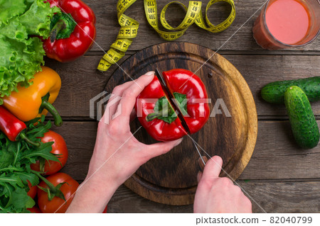 Female hands cutting pepper at table, top view Female hands cutting pepper at table, top view 82040799