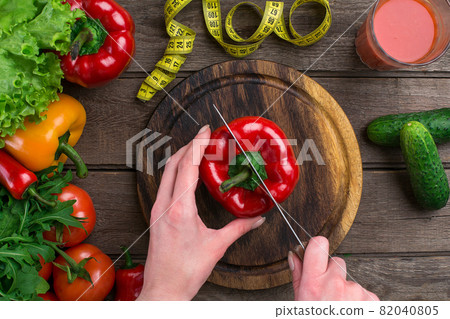 Female hands cutting pepper at table, top view Female hands cutting pepper at table, top view 82040805