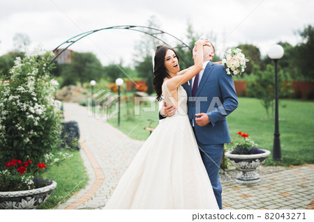 Beautiful young wedding couple posing with bouquet of flowers in hands 82043271