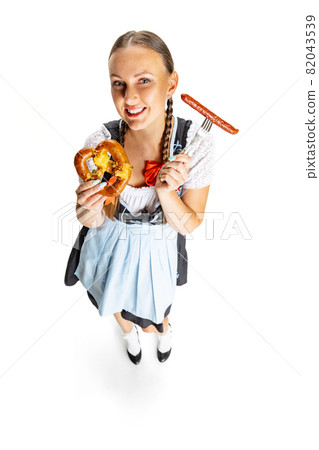High angle view of sexy Oktoberfest woman, waitress wearing a traditional Bavarian or german dirndl isolated on white studio background. High angle view of sexy Oktoberfest woman, waitress wearing a traditional Bavarian or german dirndl isolated on white studio background. 82043539